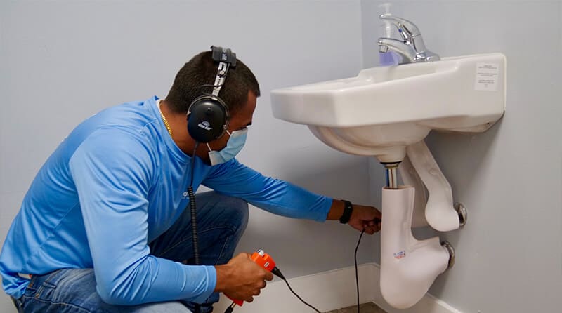 A workeris wearing ear protection while performing water leak repair